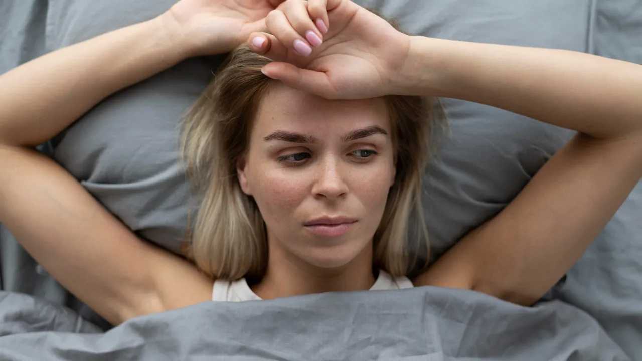 Mujer reflexionando en la cama, posiblemente afectada por trastornos del sueño.