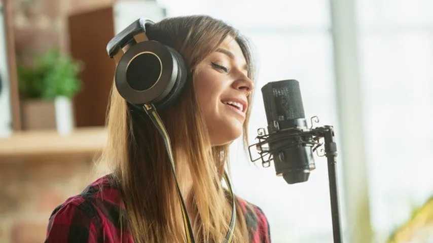 Mujer cantandp delante de un micrófono. (foto: Freepik)